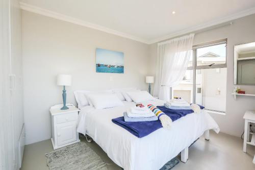 a white bedroom with a bed with towels on it at Imberbe in Struisbaai