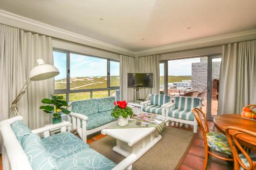 a living room with blue and white furniture and a table at Imberbe in Struisbaai