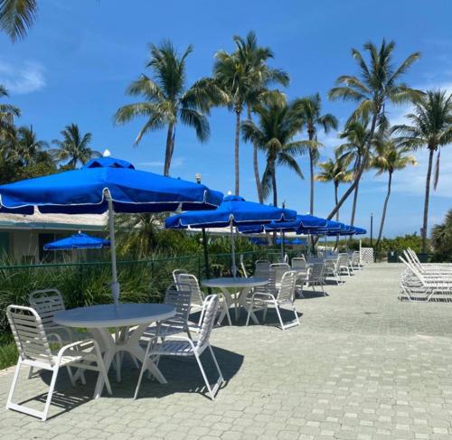 a row of tables and chairs with blue umbrellas at Silver Sands Beach Resort in Miami