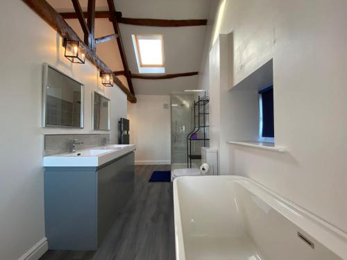 a bathroom with a tub and a sink and a toilet at Spacious 4 bedroom, 4 bathroom barn conversion home with private garden and free parking in Burn