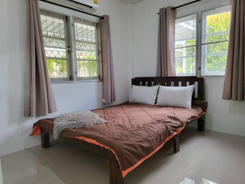 a bed sitting in a room with two windows at Minimal homey near Ruam Chok mall 15 min to city. in Chiang Mai