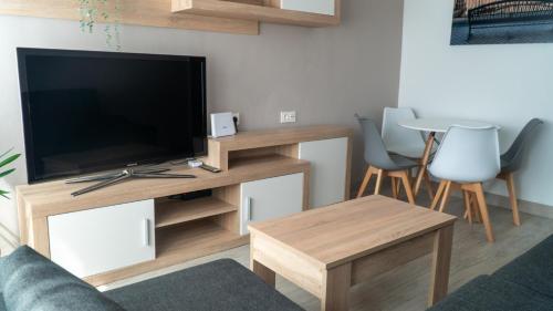 sala de estar con TV, mesa y sillas en PISO AVILES CENTRO PARQUE FERRERA, en Avilés