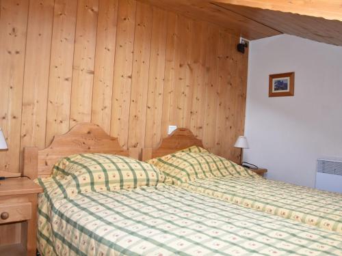 une chambre avec un lit et un mur en bois dans l'établissement Grand duplex avec balcon Sud proche pistes à Pralognan. - FR-1-464-33, à Pralognan-la-Vanoise