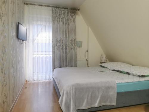 a white bedroom with a bed and a window at Pokoje i Apartament U Ireny in Poronin
