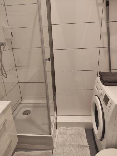 bagno con doccia e lavatrice. di Kawalerka w centrum Leszna. a Leszno