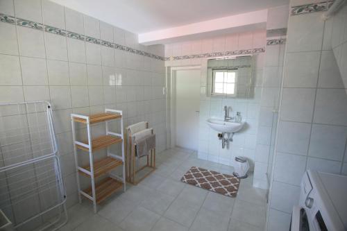 uma casa de banho em azulejos brancos com um lavatório e um chuveiro em Wohnung Rudolf em Bad Ischl
