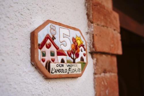 a house sign on the side of a brick wall at Casa vacanze L'Angolo Fiorito in Bettolle