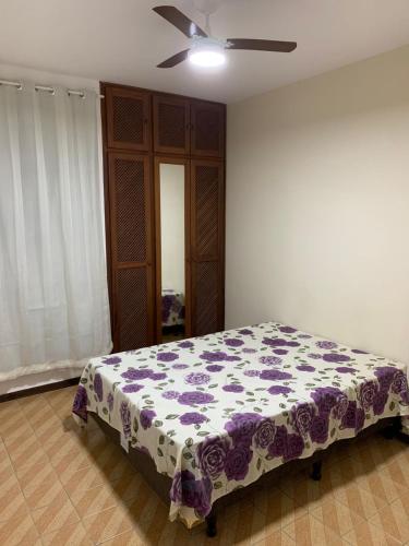 een slaapkamer met een bed met een paarse en witte deken bij APARTAMENTO PRAIA DO MORRO, 04 QUARTOS, ATE 10 PESSOAS. in Guarapari
