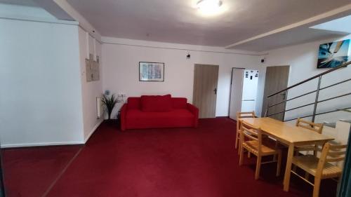 uma sala de estar com um sofá vermelho e uma mesa em Pokoje 24h ul. Bagrowa Kraków em Cracóvia