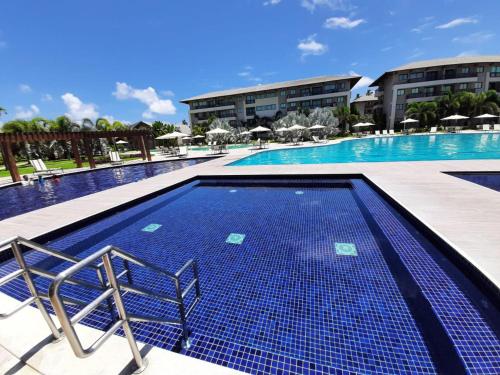 einen Pool in einem Resort mit Stühlen und Sonnenschirmen in der Unterkunft Beach Class Eco Life G005 Apartamento térreo in Porto De Galinhas