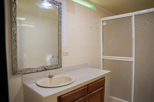 y baño con lavabo y ducha con espejo. en Rocky Cay Lodging, en San Andrés