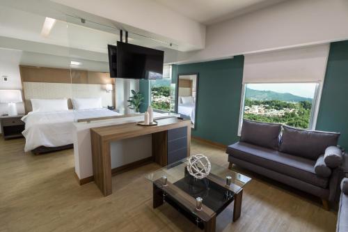 a hotel room with a bed and a couch at Holiday Inn Uruapan by IHG in Uruapan del Progreso