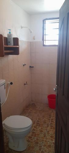 Un baño con inodoro y ducha con ventana. en Tranquil Terrace Cottages Diani, en Diani Beach