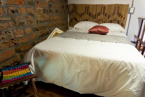 a bedroom with a large white bed with a brick wall at Casa Moore in Medellín