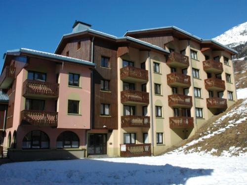 un grand bâtiment avec de la neige devant lui dans l'établissement Charmant appartement à 300m des pistes à Lanslebourg avec balcon et garage - FR-1-508-71, à Lanslebourg-Mont-Cenis