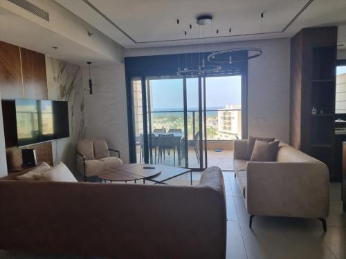 a living room with couches and a table and a tv at Apartment in Akko with Sea View in ‘Akko