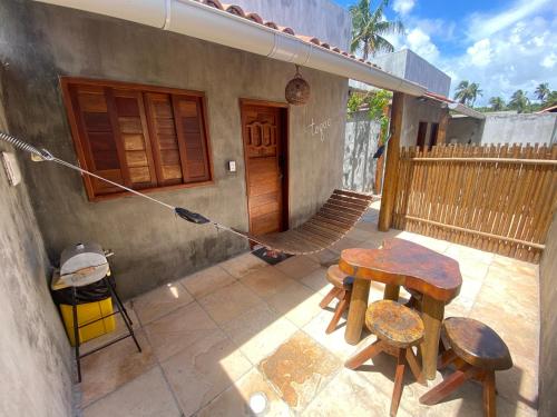 a patio with a table and chairs in front of a house at Chalé Palhano Beach in São Miguel dos Milagres