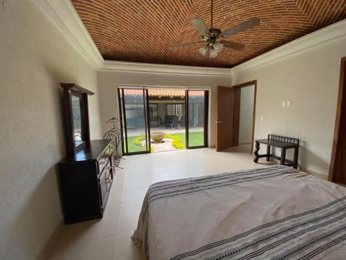 1 dormitorio con 1 cama y ventilador de techo en Villa acogedora con patio estilo hacienda., en Ajijic