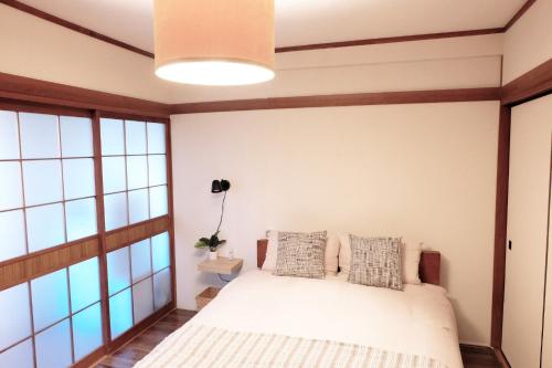 a bedroom with a white bed with windows at Daiichi Mitsumi Corporation - Vacation STAY 15351 in Musashino