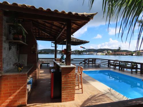 um resort com uma piscina ao lado de uma massa de água em Casa Flora em Cabo Frio