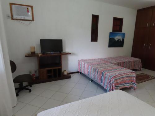 a room with two beds and a flat screen tv at Casa Flora in Cabo Frio