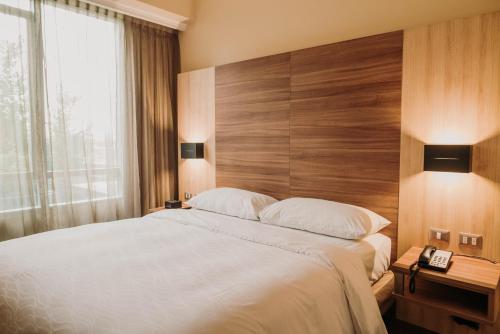 um quarto com uma cama grande e uma cabeceira em madeira em Mercure Concepcion em Concepción