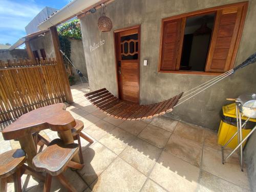 a hammock outside of a house with a table and chairs at Chalé Palhano Beach in São Miguel dos Milagres