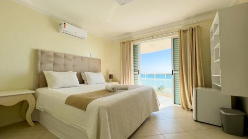 1 dormitorio con 1 cama y vistas al océano en Pousada Azores Bombinhas, en Bombinhas