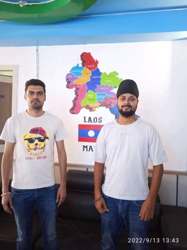 two men wearing white shirts standing in front of a map at Rainbow Hotel Vientiane in Vientiane