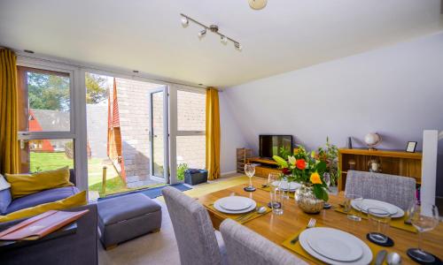 a living room with a dining room table and a couch at Escape to a Clifftop Chalet with pool and tennis onsite - 1A Kingsdown Holiday Park in Kingsdown