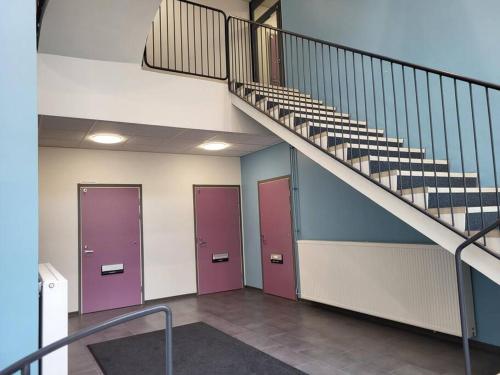 a hallway with purple doors and stairs in a building at Modern apartment near Helsinki airport in Vantaa
