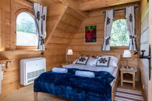 sypialnia w drewnianym domku z łóżkiem i dwoma oknami w obiekcie Dom Bajeczna Polana Jacuzzi w mieście Kościelisko