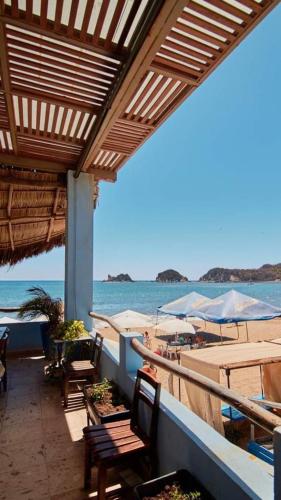 a patio with chairs and tables and the ocean at Bungalows Las Hamacas in San Patricio Melaque