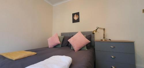 a bedroom with a bed with pillows and a dresser at Coventry Elite House in Parkside