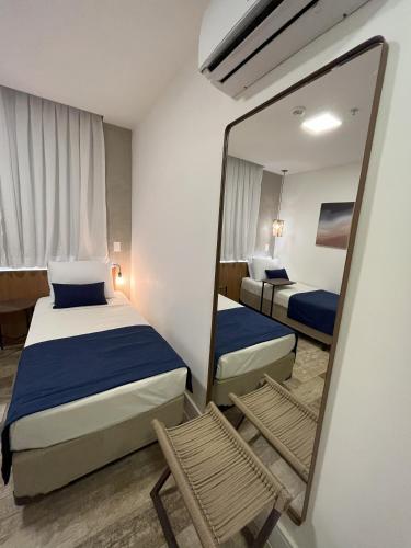 a bedroom with two beds and a mirror and a chair at Leblon Design Hotel in Rio de Janeiro