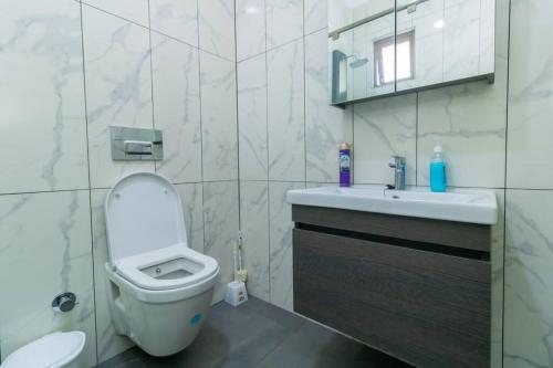 bagno bianco con servizi igienici e lavandino di Sedra home@Aqua apartments a Mombasa