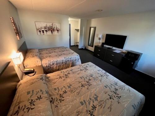 a hotel room with two beds and a flat screen tv at Kirkfield Motor Hotel in Winnipeg