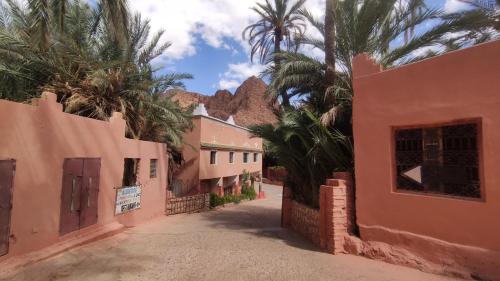 a street in a village with palm trees and buildings at Auberge Camping Garde of Eden LE LAC in Tinerhir