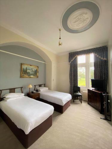 a hotel room with two beds and a television at Cave Castle Hotel in South Cave
