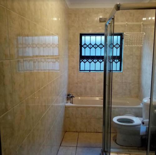 a bathroom with a shower and a toilet and a sink at Rona Thina House in Pimville
