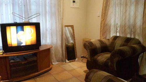 a living room with a tv and a couch and a chair at Rona Thina House in Pimville