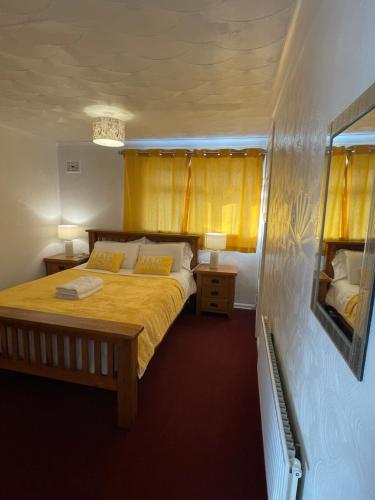 Schlafzimmer mit einem Bett mit gelber Bettwäsche und gelben Vorhängen in der Unterkunft Holiday Home Cardiff City Sleeps 7 in Cardiff
