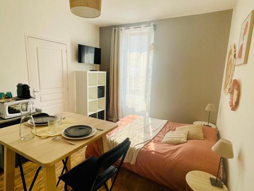 une pièce avec une table et un lit et une table et des chaises dans l'établissement L'instant - Parking gratuit - Calme, à Angoulême