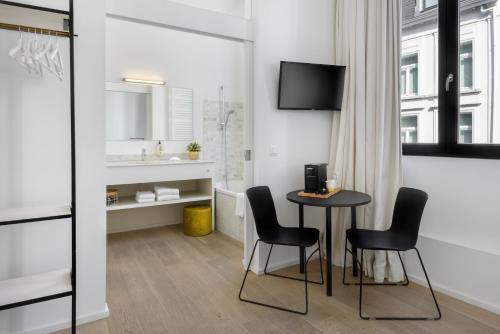 Habitación con mesa, sillas y lavabo. en The 1880 Residence by Domani Hotels en Amberes