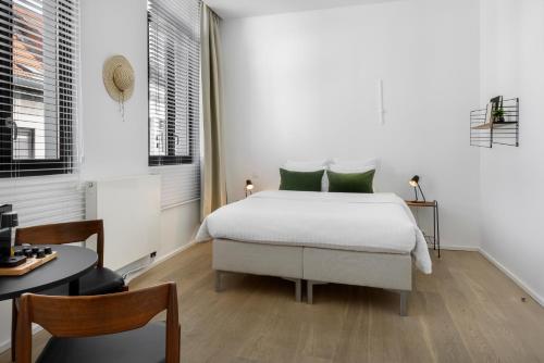 Dormitorio blanco con cama con almohadas verdes en The 1880 Residence by Domani Hotels, en Amberes