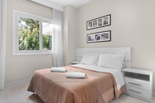 a white bedroom with a bed and a window at Residencial Altos da Bela Vista in Gramado