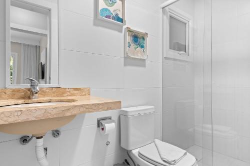 ein Badezimmer mit einem Waschbecken, einem WC und einem Spiegel in der Unterkunft Residencial Altos da Bela Vista in Gramado