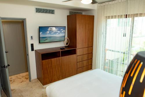 a bedroom with a bed and a tv and a window at Maya Villa Condo Hotel and Beachclub in Playa del Carmen