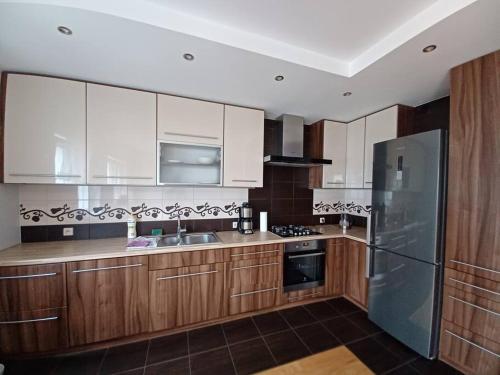 a kitchen with wooden cabinets and a stainless steel refrigerator at Przytulny Apartament w Gnieźnie in Gniezno