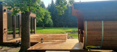 a wooden deck next to a building with a tree at Puhkemaja metsa sees in Urvaste